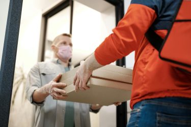 Delivery worker handing food boxes to a customer at their doorstep