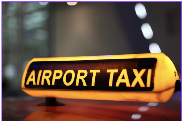 Illuminated airport taxi sign on top of a vehicle at night